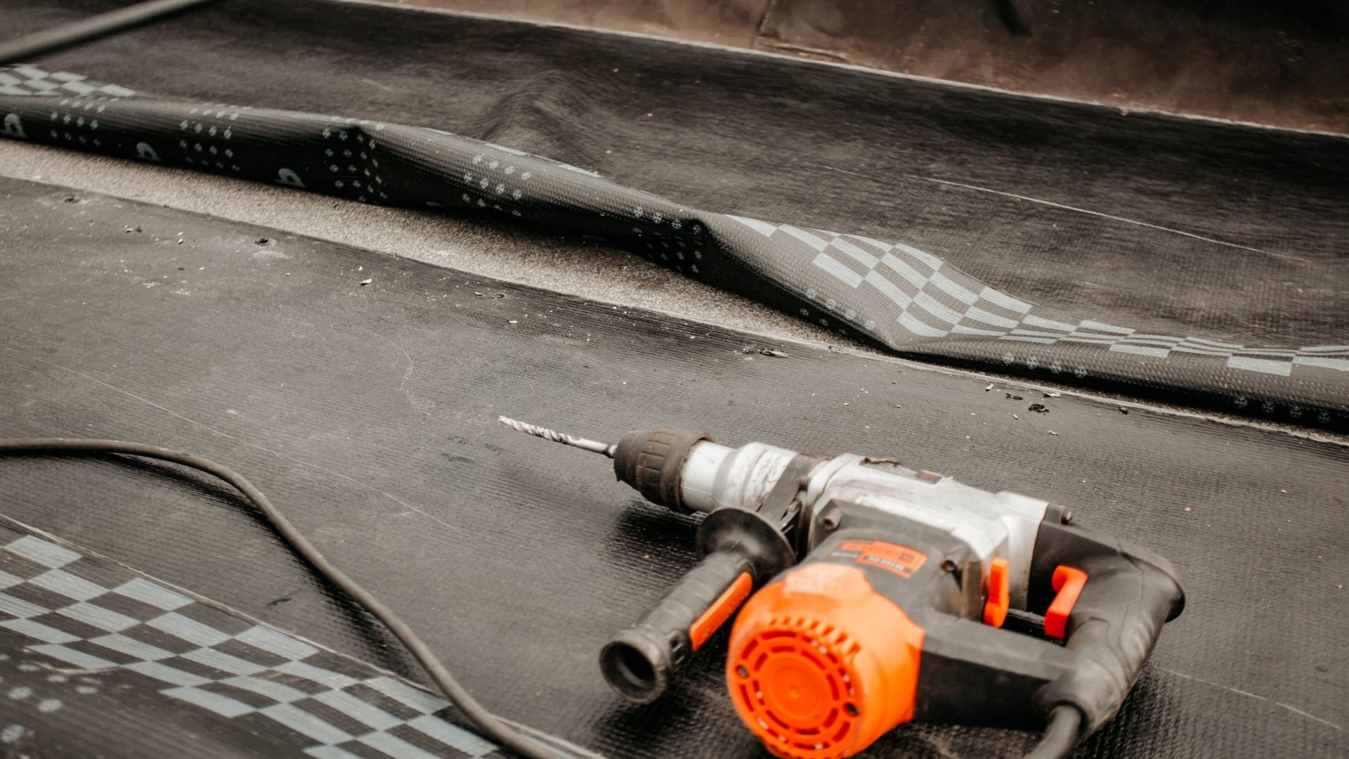 Orange and gray power drill on textured dark surface
