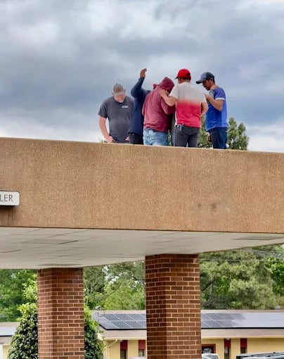 Workers collaborate on rooftop project under cloudy sky