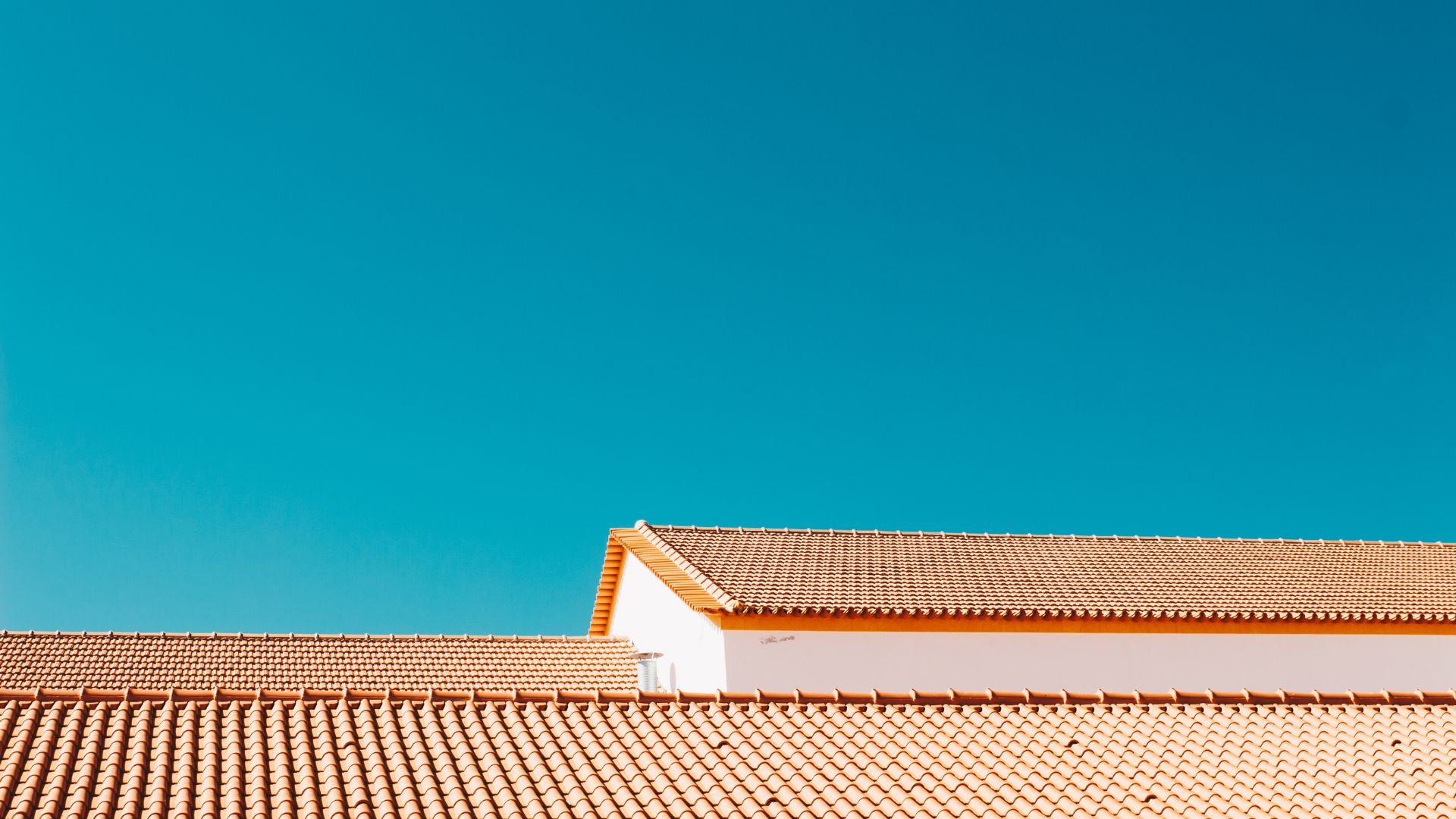 Terracotta tile roofs against bright teal sky, geometric architectural composition