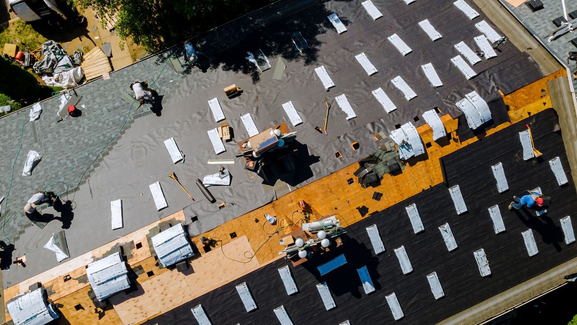 Aerial view of workers installing roofing materials on a residential building