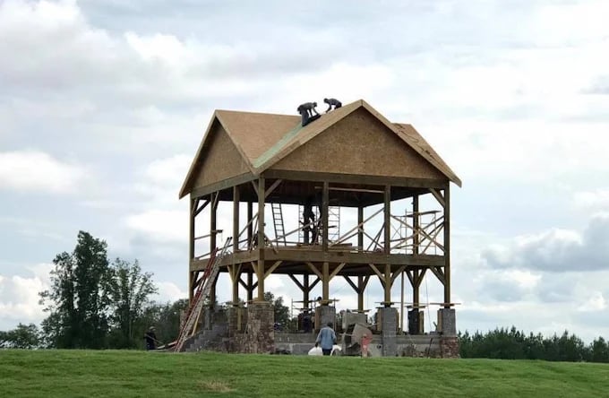 Wooden timber-frame structure under construction on stone foundation