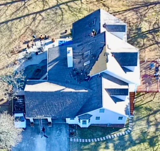 Aerial view of a suburban house with complex roof angles and driveway