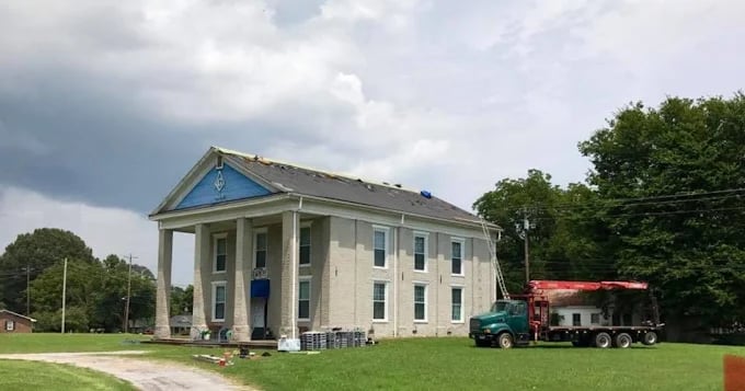 Historic building under renovation with construction truck parked nearby